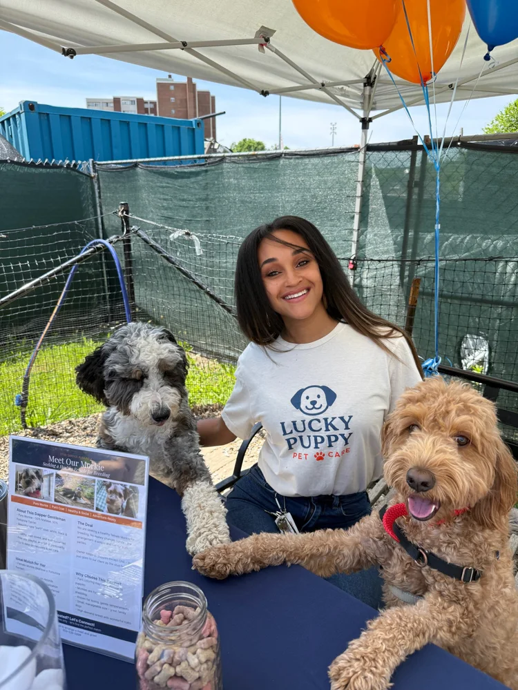 Tiffany, owner of Lucky Puppy Pet Care, smiling with two dogs at a community event